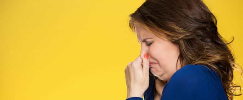 Household smells from clogged drain cause a woman to plug her nose. Yellow backdrop.