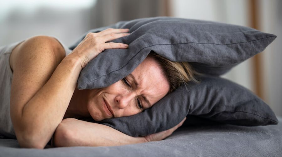 Woman holding pillow over her head to block noise